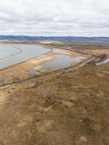 Aerial view of Lake Atanasovsko featuring its vast wetlands dry reeds and a narrow canal under a cloudy sky in Burgas Burgas Bulgaria. Aerial view of Lake Atanasovsko featuring its vast wetlands dry reeds and a narrow canal under a cloudy sky in Burgas Burgas Bulgaria.