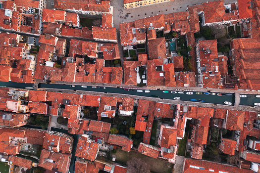 Aerial view of the historic city of Venice showing the dense network of terracotta tiled rooftops narrow canals with small boats and the intricate urban layout in Venice Veneto Italy. Aerial view of the historic city of Venice showing the dense network of terracotta tiled rooftops narrow canals with small boats and the intricate urban layout in Venice Veneto Italy.