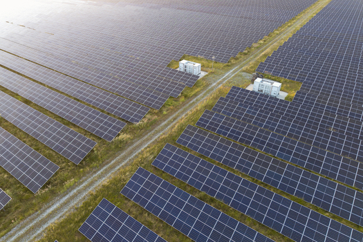 Aerial view of a large solar farm with rows of photovoltaic panels a dirt access path and small utility buildings in Poland. Aerial view of a large solar farm with rows of photovoltaic panels a dirt access path and small utility buildings in Poland.