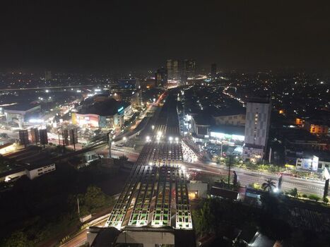 Aerial view of the illuminated highway overpass and urban cityscape at night with traffic streaks and surrounding buildings in Bekasi Barat West Java Indonesia. Aerial view of the illuminated highway overpass and urban cityscape at night with traffic streaks and surrounding buildings in Bekasi Barat West Java Indonesia.