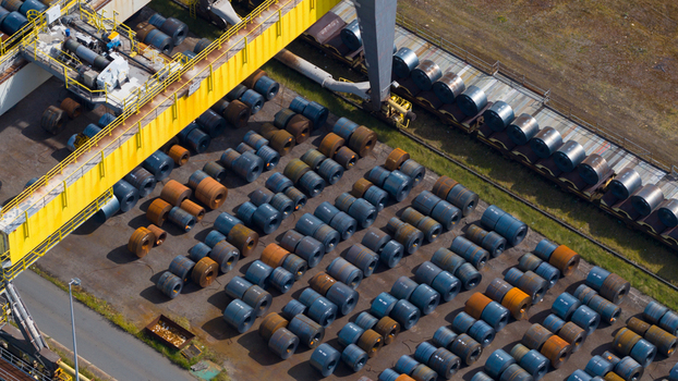 Aerial view of the Tata Steel plant featuring rows of large steel coils and industrial machinery under bright daylight in Velsen Noord Noord Holland Netherlands. Aerial view of the Tata Steel plant featuring rows of large steel coils and industrial machinery under bright daylight in Velsen Noord Noord Holland Netherlands.