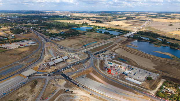 Aerial view of Black Cat Roundabout highway construction featuring civil engineering work bridge structures heavy machinery and surrounding ponds in Chawston England United Kingdom. Aerial view of Black Cat Roundabout highway construction featuring civil engineering work bridge structures heavy machinery and surrounding ponds in Chawston England United Kingdom.