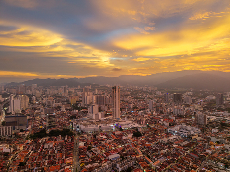 George Town Malaysia 22 September 2026 Aerial view of George Town cityscape at sunset with golden light over urban skyline high rise buildings and dense rooftops against distant mountains.