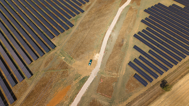 Aerial view of Eaton Socon solar farm and battery energy storage systems with rows of photovoltaic panels a dirt path and a small green vehicle in St. Neots England United Kingdom. Aerial view of Eaton Socon solar farm and battery energy storage systems with rows of photovoltaic panels a dirt path and a small green vehicle in St. Neots England United Kingdom.