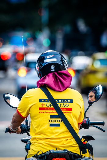 Rio de Janeiro Brazil 13 June 2026 View of a delivery person on a motorcycle wearing a yellow uniform and helmet navigating through urban traffic in the Copacabana neighborhood.