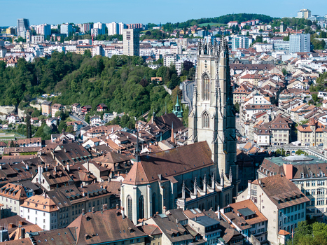 Aerial view of St Nicolas Cathedral with its gothic tower rising above the historic rooftops and lush green hills in Fribourg Fribourg Switzerland. Aerial view of St Nicolas Cathedral with its gothic tower rising above the historic rooftops and lush green hills in Fribourg Fribourg Switzerland.