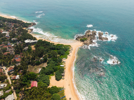 Aerial view of the tropical coastline featuring sandy beaches turquoise ocean waves and lush palm trees in Dodanduwa Southern Province Sri Lanka. Aerial view of the tropical coastline featuring sandy beaches turquoise ocean waves and lush palm trees in Dodanduwa Southern Province Sri Lanka.