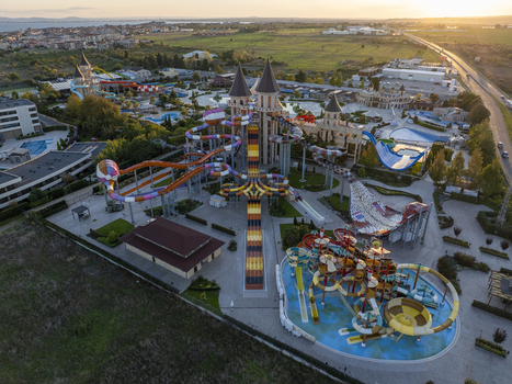 Aerial view of a large water park featuring colorful water slides swimming pools and castle themed structures during golden hour in Bulgaria. Aerial view of a large water park featuring colorful water slides swimming pools and castle themed structures during golden hour in Bulgaria.