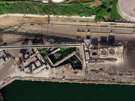 Aerial view of an industrial facility with conveyor belts storage tanks and concrete structures situated along the waterfront in Bajos de Haina San Cristobal Provinc Dominican Republic.