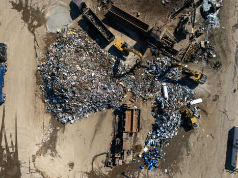 Aerial view of a scrap metal recycling facility with large piles of scrap metal heavy excavators and industrial machinery in a yard in Carson California United States.