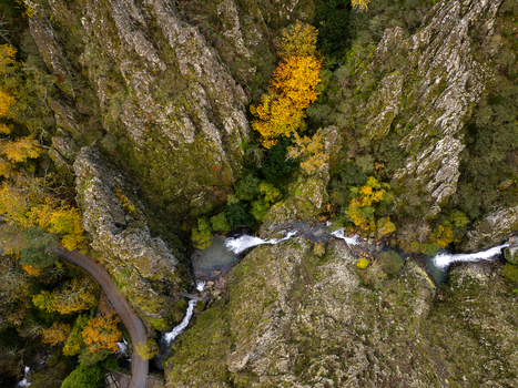 Aerial view of Poco do Inferno waterfall cascading through steep rocky cliffs and vibrant autumn foliage in Manteigas Guarda District Portugal. Aerial view of Poco do Inferno waterfall cascading through steep rocky cliffs and vibrant autumn foliage in Manteigas Guarda District Portugal.