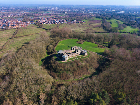 Aerial view of Stafford Castle ruins standing proudly atop a hill amidst a sea of trees contrasting with the green grass Newport Road Stafford England United Kingdom. Aerial view of Stafford Castle ruins standing proudly atop a hill amidst a sea of trees contrasting with the green grass Newport Road Stafford England United Kingdom.