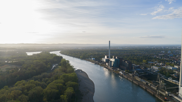 Aerial view of the Grosskraftwerk Mannheim power plant along the Rhine river with industrial infrastructure and forest under soft sunset light in Mannheim Baden Wurttemberg Germany.