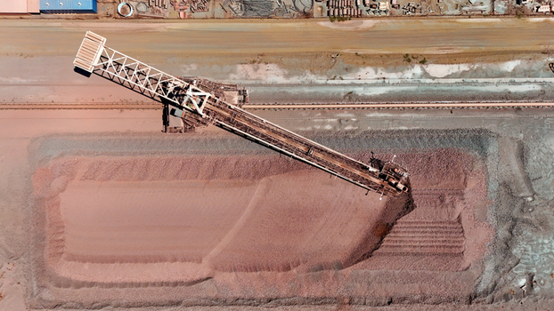 Aerial view of a massive conveyor belt system diligently piling reddish brown ore creating a striking contrast against the industrial landscape Rustenburg North West South Africa. Aerial view of a massive conveyor belt system diligently piling reddish brown ore creating a striking contrast against the industrial landscape Rustenburg North West South Africa.
