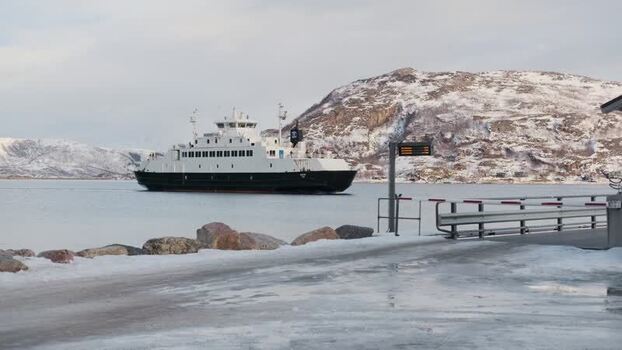 View of a ferry at the snowy Brensholmen dock Norway.