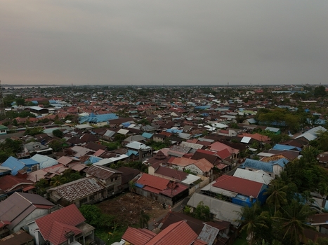 Aerial view of the dense urban landscape of Banjarmasin City featuring residential rooftops narrow streets and tropical vegetation in Banjarmasin City South Kalimantan Indonesia. Aerial view of the dense urban landscape of Banjarmasin City featuring residential rooftops narrow streets and tropical vegetation in Banjarmasin City South Kalimantan Indonesia.
