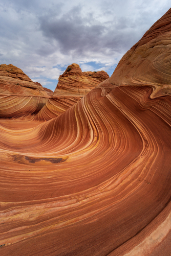 View of the undulating sandstone rock formations of The Wave with swirling orange and red stripes under a cloudy sky in Kanab Arizona United States. View of the undulating sandstone rock formations of The Wave with swirling orange and red stripes under a cloudy sky in Kanab Arizona United States.