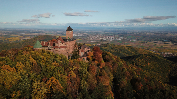 Aerial view of Chateau du Haut Koenigsbourg surrounded by autumn forests on a hillside with a distant valley landscape in Orschwiller Grand Est France.