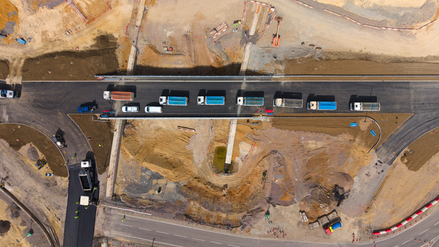 Aerial view of Black Cat Roundabout highway construction showing heavy trucks on a new road section with earthworks and civil engineering infrastructure in Chawston England United Kingdom. Aerial view of Black Cat Roundabout highway construction showing heavy trucks on a new road section with earthworks and civil engineering infrastructure in Chawston England United Kingdom.