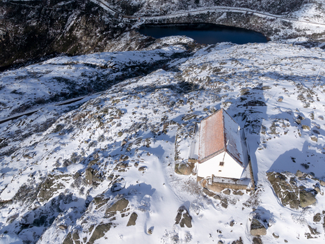Aerial view of a snow dusted landscape with a small white building and a dark lake in the distance Lagoa Comprida São Romão Serra da Estrella Portugal. Aerial view of a snow dusted landscape with a small white building and a dark lake in the distance Lagoa Comprida São Romão Serra da Estrella Portugal.