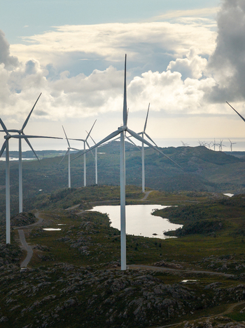 Aerial view of Makaknuten Vindkraftverk wind farm with large white turbines set against a rugged landscape of rocky hills small ponds and a cloudy sky in Bjerkreim Municipality Rogaland Norway. Aerial view of Makaknuten Vindkraftverk wind farm with large white turbines set against a rugged landscape of rocky hills small ponds and a cloudy sky in Bjerkreim Municipality Rogaland Norway.