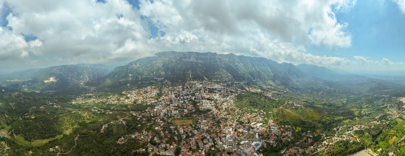 Aerial view of the historic town of Kruje nestled at the foot of the rugged Skanderbeg Mountains with red tiled rooftops and lush green hillsides in Kruje Durres County Albania.