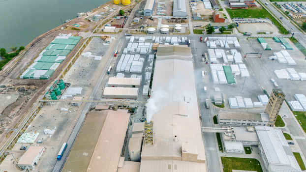 Aerial view of an industrial complex with large warehouses stacks of materials and a smoking chimney in Sabac Vojvodina Serbia. Aerial view of an industrial complex with large warehouses stacks of materials and a smoking chimney in Sabac Vojvodina Serbia.