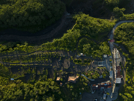 Aerial view of Bunker Kaliadem Merapi surrounded by lush green forests and volcanic terrain under warm sunlight in Kecamatan Pakem Daerah Istimewa Yogya Indonesia. Aerial view of Bunker Kaliadem Merapi surrounded by lush green forests and volcanic terrain under warm sunlight in Kecamatan Pakem Daerah Istimewa Yogya Indonesia.