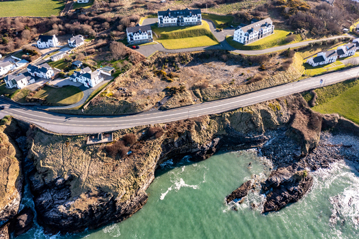 Aerial view of Portnablagh featuring coastal cliffs a winding road and residential buildings overlooking the Atlantic Ocean in Portnablagh County Donegal Ireland. Aerial view of Portnablagh featuring coastal cliffs a winding road and residential buildings overlooking the Atlantic Ocean in Portnablagh County Donegal Ireland.