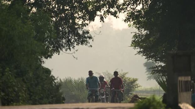View of people riding bicycles on a rural road in Bogura Bangladesh.