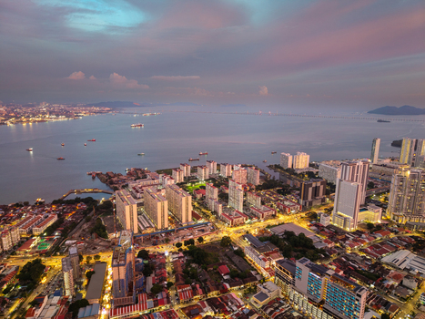 George Town Penang Malaysia 22 September 2026 Aerial view of the George Town cityscape at twilight featuring high rise buildings illuminated streets and the coastal waterfront under a sunset sky.