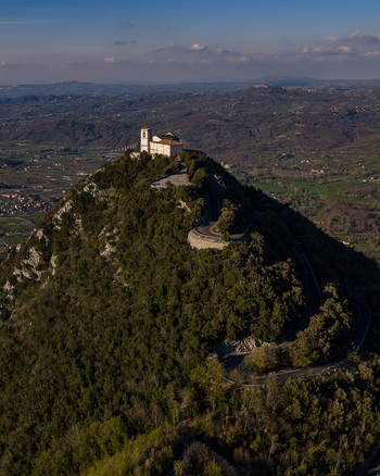 Aerial view of Santuario del Santissimo Salvatore on a lush green hilltop with a winding road and the valley in the background Montella Campania Italy. Aerial view of Santuario del Santissimo Salvatore on a lush green hilltop with a winding road and the valley in the background Montella Campania Italy.