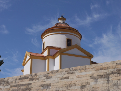 View of the Calvary Chapel with its distinctive dome and yellow trim rising above a stone wall under a clear blue sky in Portalegre Portalegre Portugal. View of the Calvary Chapel with its distinctive dome and yellow trim rising above a stone wall under a clear blue sky in Portalegre Portalegre Portugal.