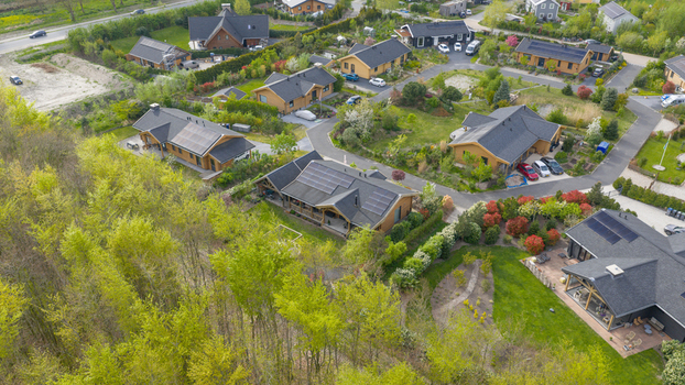 Aerial view of Ecodorp Bolderburen featuring modern wooden houses with solar panels lush gardens and winding paths surrounded by green trees in Almere Flevoland Netherlands. Aerial view of Ecodorp Bolderburen featuring modern wooden houses with solar panels lush gardens and winding paths surrounded by green trees in Almere Flevoland Netherlands.