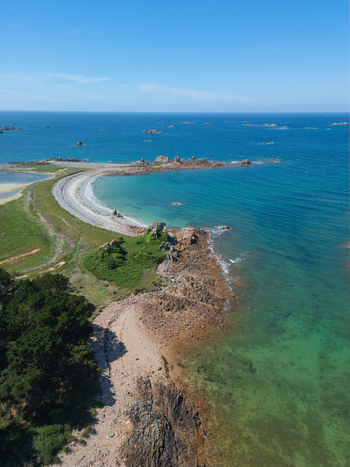 Aerial view of the crescent shaped Plage de Port Blanc with turquoise waters rocky outcrops and green coastal vegetation in Penvenan Bretagne France. Aerial view of the crescent shaped Plage de Port Blanc with turquoise waters rocky outcrops and green coastal vegetation in Penvenan Bretagne France.