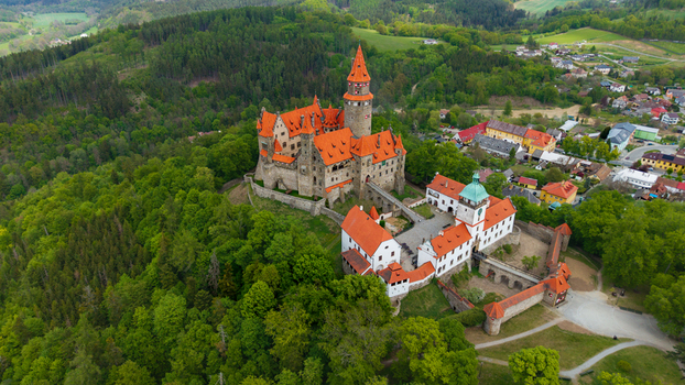 Aerial view of Bouzov Castle with its iconic red roofs and tall tower surrounded by lush green forests in Bouzov Olomoucky kraj Czechia. Aerial view of Bouzov Castle with its iconic red roofs and tall tower surrounded by lush green forests in Bouzov Olomoucky kraj Czechia.