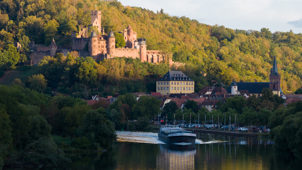 Aerial view of Wertheim Castle overlooking the historic town and the Main river with a cargo boat surrounded by lush hills in the golden hour light in Wertheim Baden Wurttemberg Germany. Aerial view of Wertheim Castle overlooking the historic town and the Main river with a cargo boat surrounded by lush hills in the golden hour light in Wertheim Baden Wurttemberg Germany.