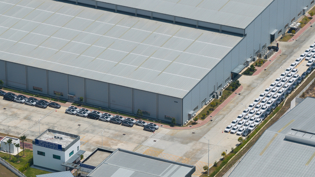 Aerial view of the BYD AUTO THAILAND factory with rows of new electric vehicles parked outside the large industrial warehouse in Phananikhom Rayong Thailand.