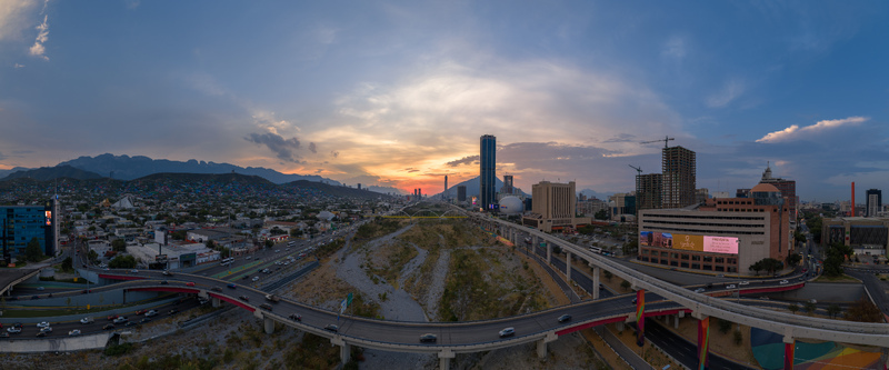 Aerial view of the Monterrey skyline at sunset featuring the Santa Catarina River skyscrapers highway infrastructure and the Sierra Madre mountains Monterrey Nuevo Leon Mexico. Aerial view of the Monterrey skyline at sunset featuring the Santa Catarina River skyscrapers highway infrastructure and the Sierra Madre mountains Monterrey Nuevo Leon Mexico.