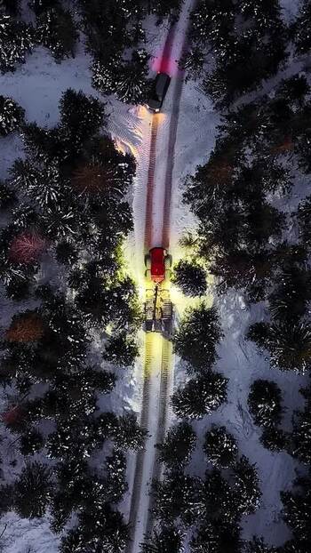 Aerial view of snowcat moving through a snowy forest in Latvia.