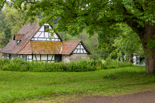 View of the historic half timbered house at Hennebergisches Museum Kloster Vessra with its red tiled roof surrounded by lush green grass and trees in Kloster Vessra Thuringen Germany.