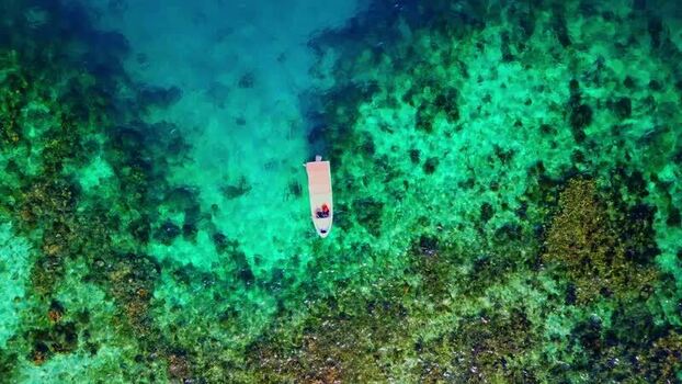 Aerial view of a small boat on turquoise water in Guanaja Honduras. Aerial view of a small boat on turquoise water in Guanaja Honduras.