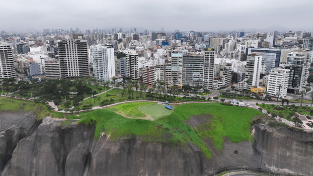 Aerial view of the Barranco district featuring coastal cliffs lush green parks and a dense urban skyline with modern high rise buildings in Barranco Lima Province Peru. Aerial view of the Barranco district featuring coastal cliffs lush green parks and a dense urban skyline with modern high rise buildings in Barranco Lima Province Peru.