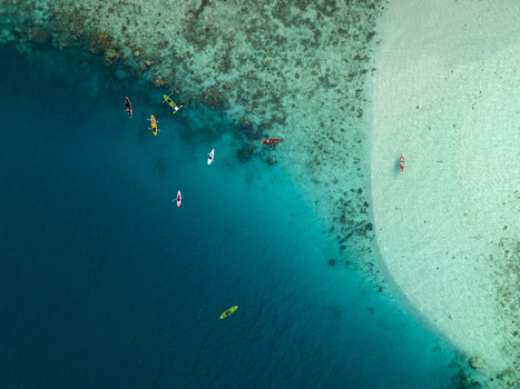 Aerial view of kayaks and paddleboards scattered across the turquoise waters near Menjangan Kecil Island contrasting with the white sandy beach Karimunjawa Central Java Indonesia.