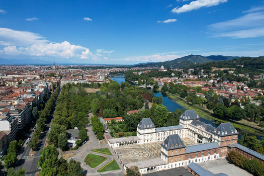 Aerial view of Castello del Valentino historic palace along the Po River with lush greenery and the city skyline in Torino Piemonte Italy. Aerial view of Castello del Valentino historic palace along the Po River with lush greenery and the city skyline in Torino Piemonte Italy.