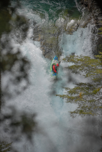 View of a kayaker navigating the white water rapids of the Rio Manso surrounded by lush green trees in San Carlos de Bariloche Rio Negro Argentina. View of a kayaker navigating the white water rapids of the Rio Manso surrounded by lush green trees in San Carlos de Bariloche Rio Negro Argentina.
