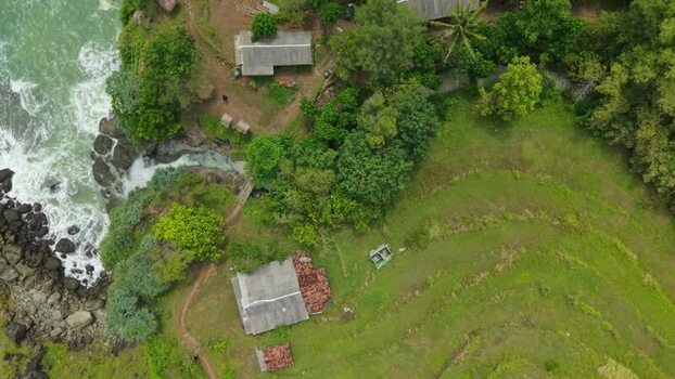 Aerial view of Banyu Tibo Waterfall and rocky coastline Indonesia.