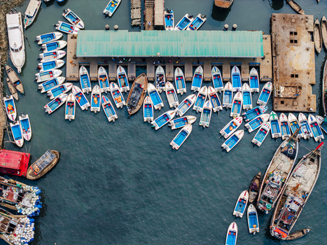 Moheskhali Upazila Bangladesh 11 March 2026 Aerial view of numerous small boats moored at a busy pier with a green roof and larger wooden vessels in the water. Moheskhali Upazila Bangladesh 11 March 2026 Aerial view of numerous small boats moored at a busy pier with a green roof and larger wooden vessels in the water.