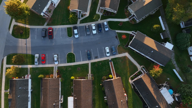 Aerial view of a residential neighborhood featuring parked cars in a parking lot houses with dark roofs and autumn trees in East Lampeter Township Pennsylvania United States. Aerial view of a residential neighborhood featuring parked cars in a parking lot houses with dark roofs and autumn trees in East Lampeter Township Pennsylvania United States.