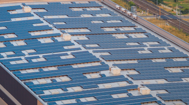 Alixan France 25 July 2026 Aerial view of a modern industrial warehouse roof covered with photovoltaic solar panels featuring adjacent railway lines and industrial infrastructure.